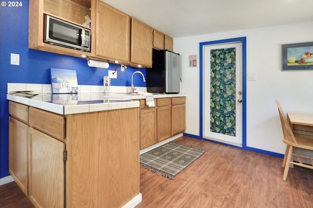 kitchen featuring tile countertops, light hardwood / wood-style floors, sink, and stainless steel appliances