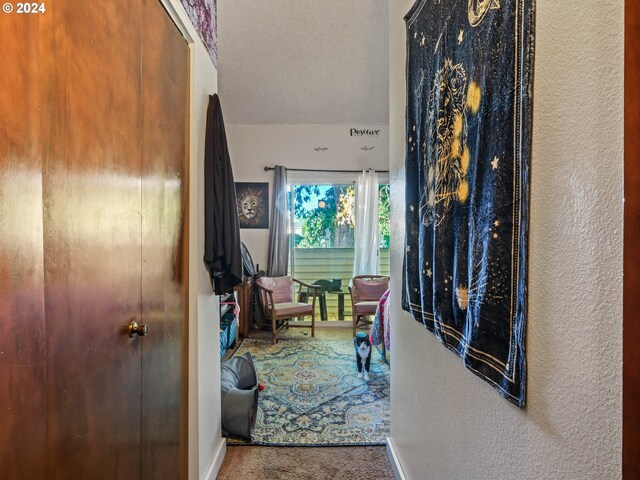 hall with carpet flooring and a textured ceiling