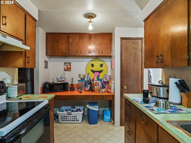 kitchen with a textured ceiling, black appliances, and sink