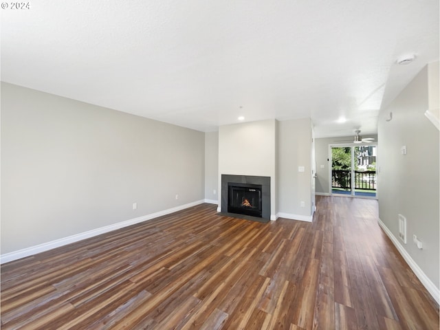 unfurnished living room featuring ceiling fan and dark hardwood / wood-style flooring