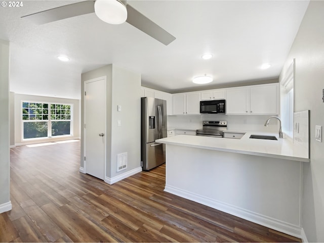 kitchen with kitchen peninsula, white cabinetry, dark wood-type flooring, appliances with stainless steel finishes, and sink