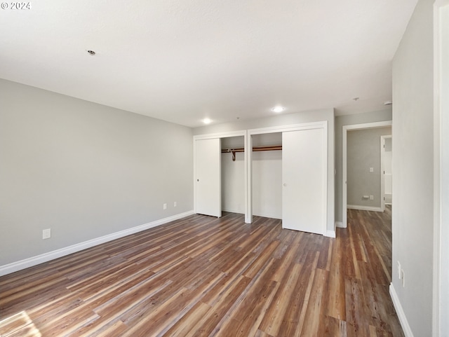 unfurnished bedroom with multiple closets and wood-type flooring