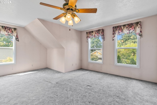 additional living space featuring ceiling fan, vaulted ceiling, light colored carpet, and a textured ceiling