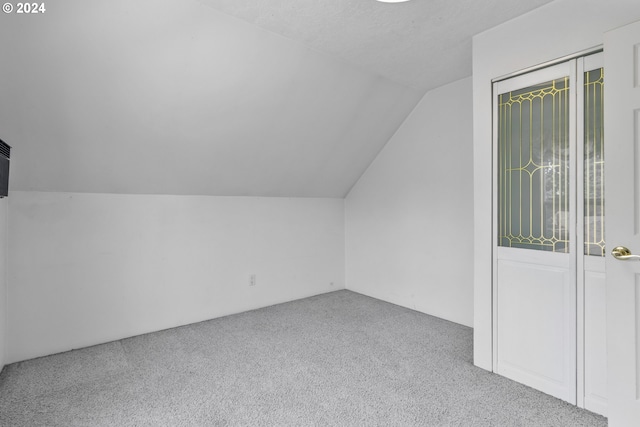 bonus room with light carpet, vaulted ceiling, and a textured ceiling