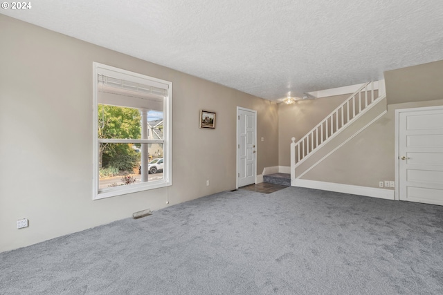 unfurnished living room featuring carpet flooring and a textured ceiling