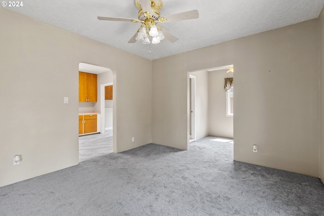 carpeted empty room with ceiling fan and a textured ceiling