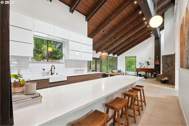 bar featuring high vaulted ceiling, white cabinets, sink, decorative light fixtures, and wood ceiling