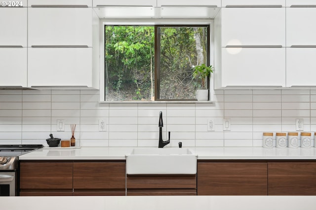 kitchen featuring stainless steel range with electric cooktop, modern cabinets, a sink, and tasteful backsplash