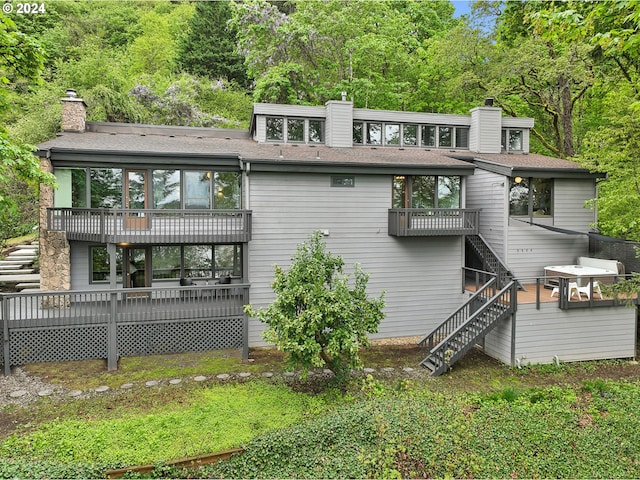 rear view of property featuring stairway, a chimney, and a deck