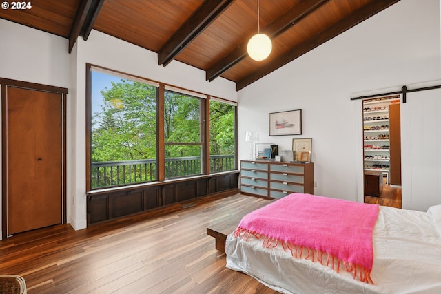 bedroom with a barn door, wooden ceiling, wood finished floors, and vaulted ceiling with beams