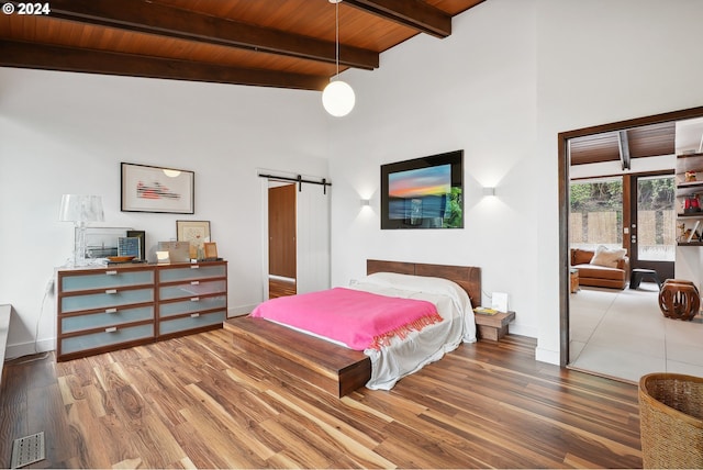 bedroom featuring a barn door, wood finished floors, a towering ceiling, and wooden ceiling