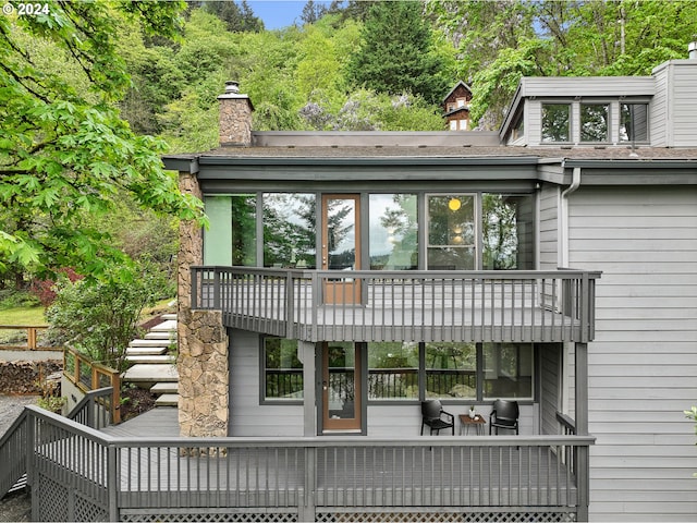 back of house with a chimney, a balcony, and a deck