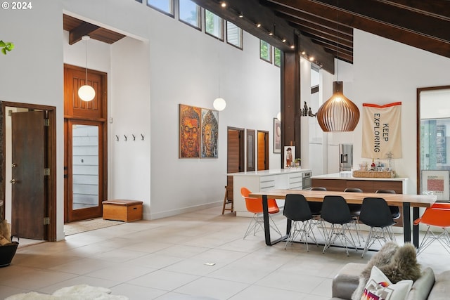 interior space featuring beamed ceiling, baseboards, high vaulted ceiling, and light tile patterned floors