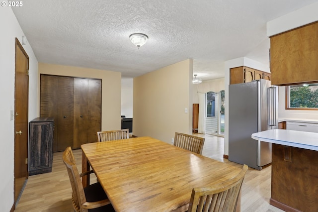 dining room featuring a textured ceiling and light hardwood / wood-style flooring