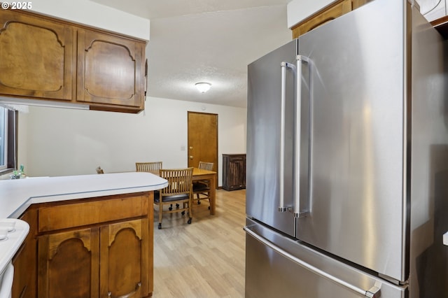 kitchen featuring light hardwood / wood-style flooring, high end refrigerator, and a textured ceiling