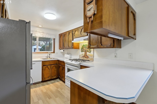 kitchen featuring sink, white appliances, kitchen peninsula, and light wood-type flooring