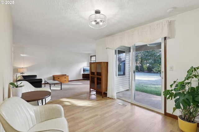 interior space featuring an inviting chandelier, a textured ceiling, and light hardwood / wood-style floors