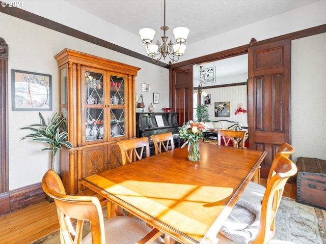 dining area with light wood-type flooring and an inviting chandelier