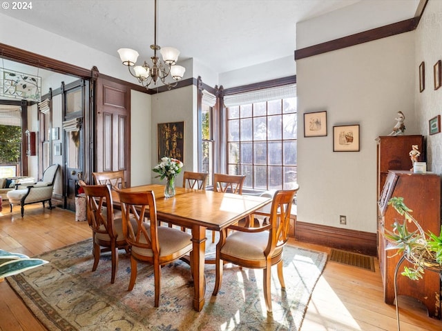 dining area featuring a barn door, a notable chandelier, and light hardwood / wood-style floors