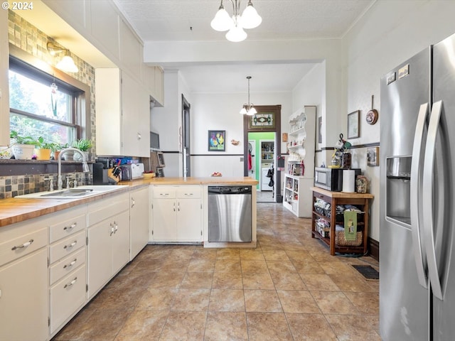 kitchen featuring decorative backsplash, white cabinets, decorative light fixtures, and stainless steel appliances