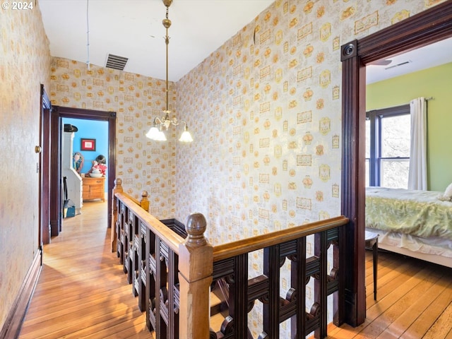 hallway featuring a chandelier and light hardwood / wood-style flooring