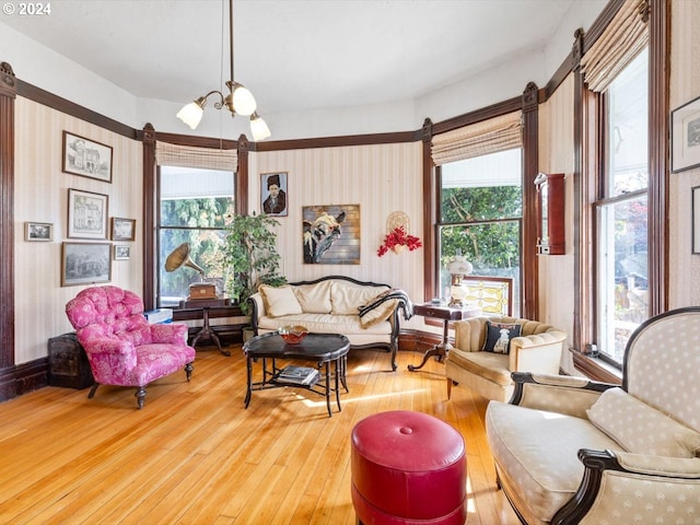 sitting room with a wealth of natural light, wood-type flooring, and a chandelier