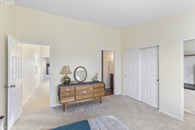 bedroom with ensuite bathroom and light colored carpet