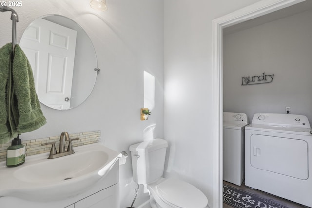 bathroom with washing machine and clothes dryer, backsplash, vanity, and toilet