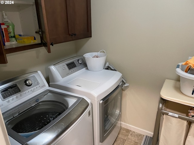 clothes washing area with cabinets, light tile patterned floors, and separate washer and dryer