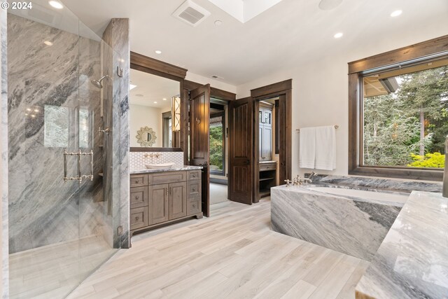 bathroom with backsplash, a healthy amount of sunlight, oversized vanity, and independent shower and bath