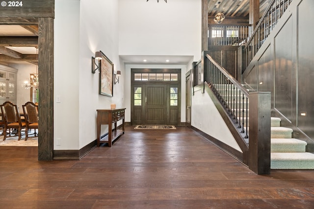 foyer with hardwood / wood-style flooring, beamed ceiling, a high ceiling, and a chandelier