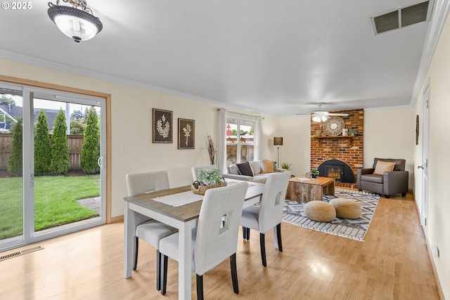 18685 SW Hennig Ct, Beaverton, OR 97003 - dining area with light wood finished floors, a brick fireplace, ornamental molding, and ceiling fan