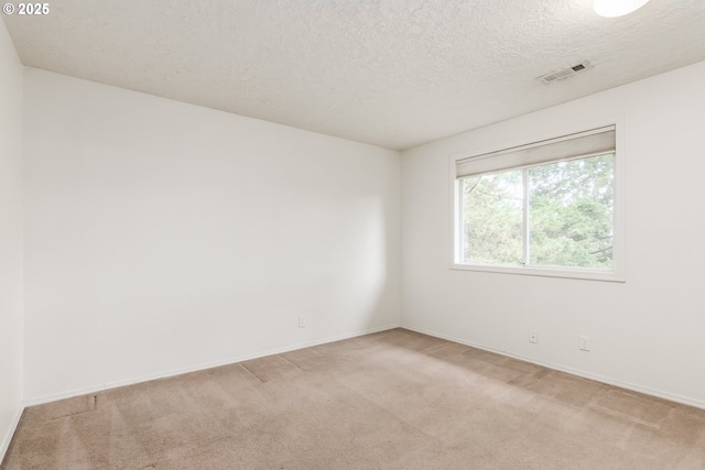 unfurnished room with baseboards, visible vents, light carpet, and a textured ceiling