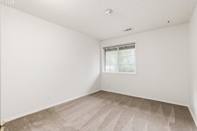 spare room featuring baseboards, visible vents, a textured ceiling, and carpet flooring