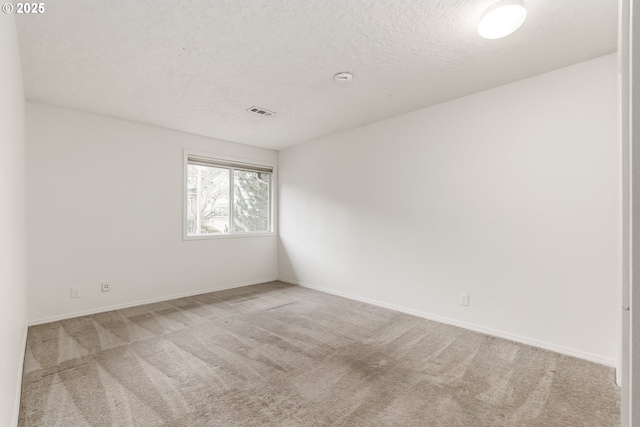 carpeted empty room with a textured ceiling, visible vents, and baseboards