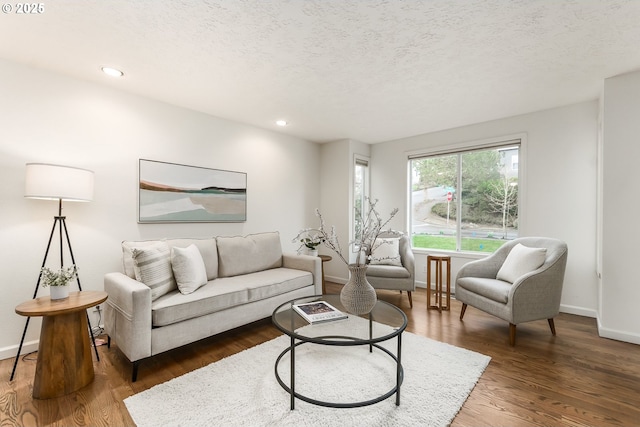 living room with recessed lighting, a textured ceiling, baseboards, and wood finished floors