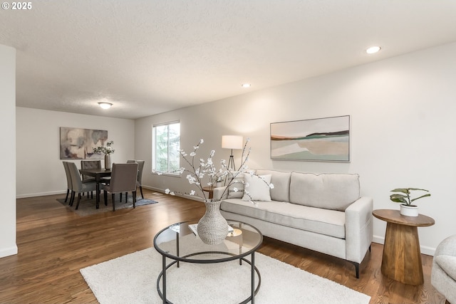 living area with a textured ceiling, baseboards, wood finished floors, and recessed lighting