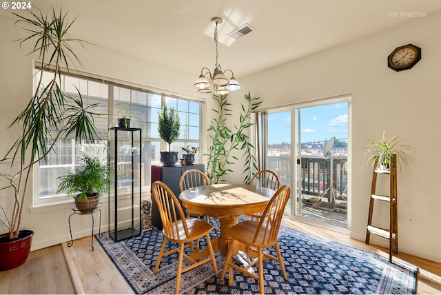 dining area with a healthy amount of sunlight, a chandelier, and light hardwood / wood-style floors