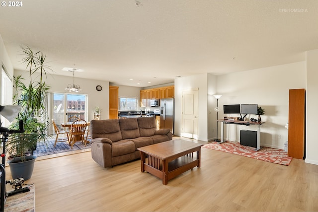 living room with an inviting chandelier and light wood-type flooring