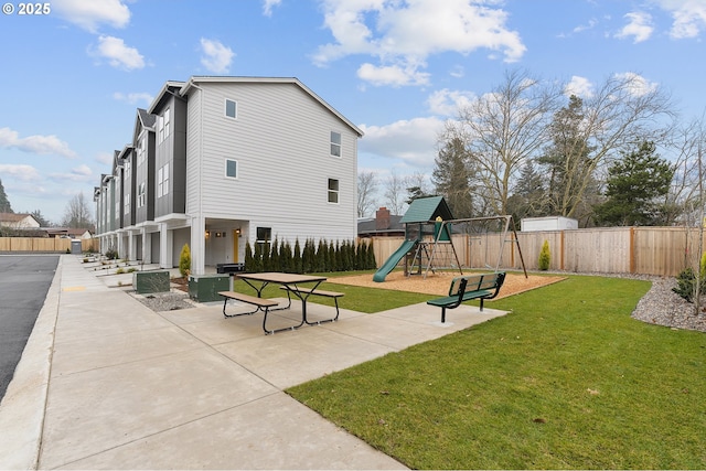 view of community featuring a playground, a patio area, and a lawn