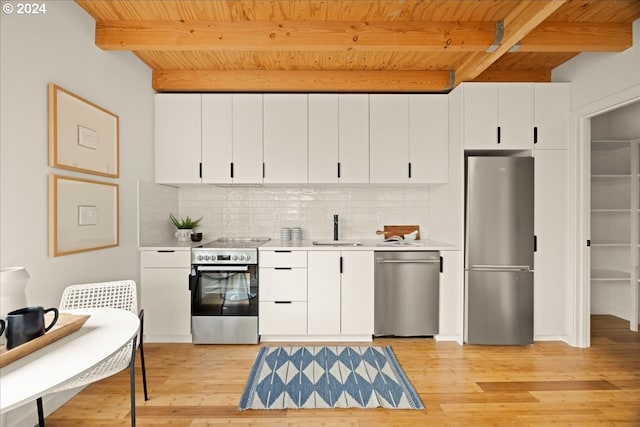 kitchen featuring white cabinets, tasteful backsplash, stainless steel appliances, beamed ceiling, and light hardwood / wood-style floors