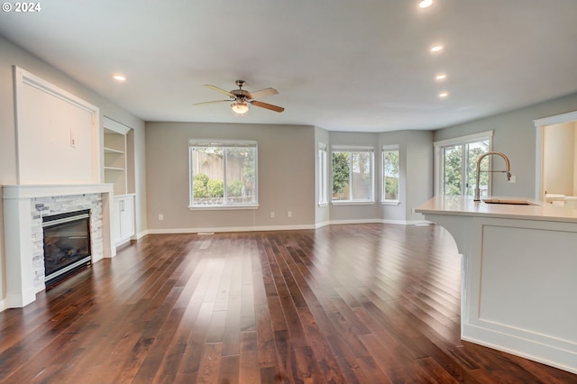 unfurnished living room with plenty of natural light, dark hardwood / wood-style floors, sink, and a fireplace