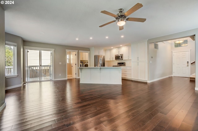 unfurnished living room with separate washer and dryer, ceiling fan, and dark hardwood / wood-style floors