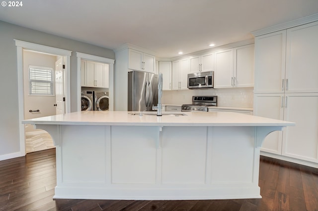 kitchen with washing machine and dryer, white cabinetry, a large island with sink, and appliances with stainless steel finishes