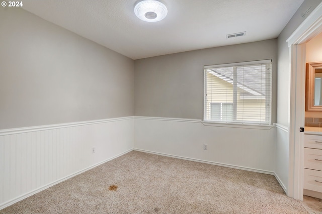 empty room with light carpet and a textured ceiling