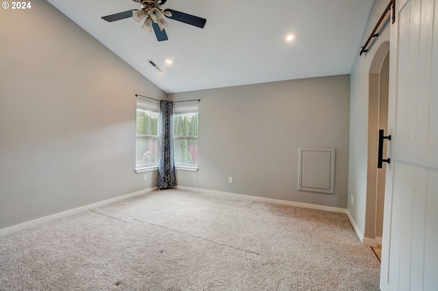 spare room with ceiling fan, a barn door, light colored carpet, and lofted ceiling