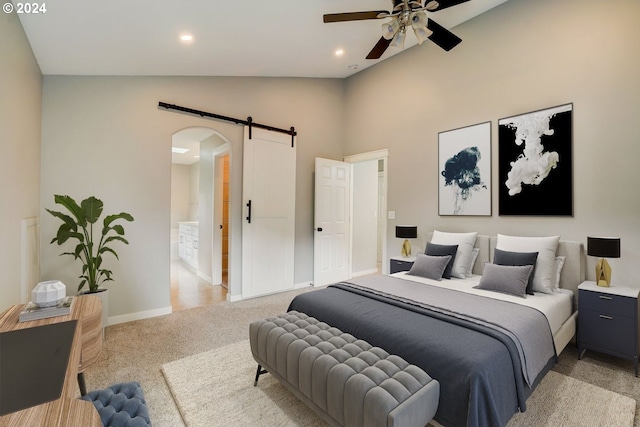 bedroom with light carpet, vaulted ceiling, ceiling fan, a barn door, and connected bathroom