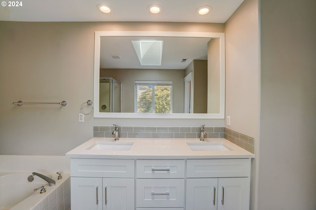 bathroom featuring vanity, a relaxing tiled tub, and a skylight