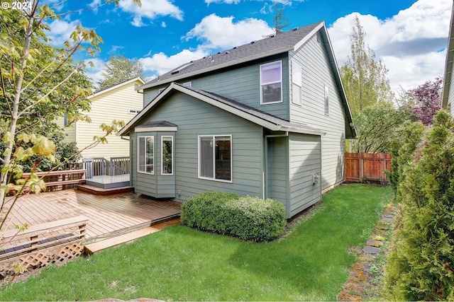 rear view of property featuring a lawn and a wooden deck