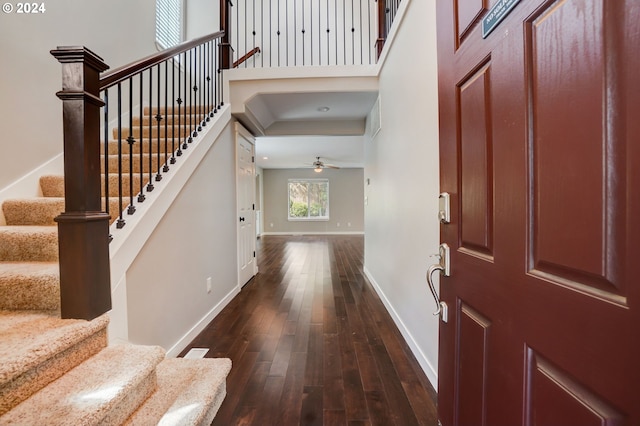 foyer entrance with ceiling fan and dark wood-type flooring